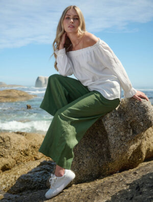 Model sitting on a boulder wearing Lea Green Linen Pants and a white shirt.